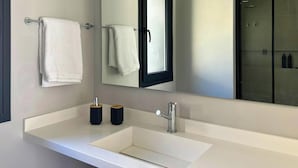 A modern bathroom with a white sink, two black soap dispensers, a mirror, and a towel rack. - Casiraaaaa (Purmamarca)