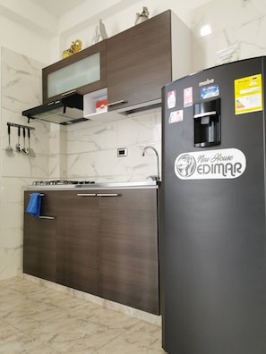 A kitchen with a black refrigerator, a stove, a sink, and a microwave. - Apartamento Confortable. Edimar 301 (Magdalena)