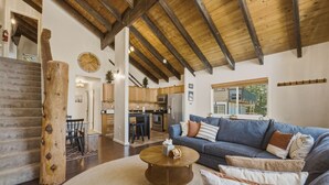 A spacious living area with a wooden ceiling, a sofa set, a coffee table, and a staircase. - Cozy Alpine Retreat | BBQ, Views + Fireplace (Stateline)