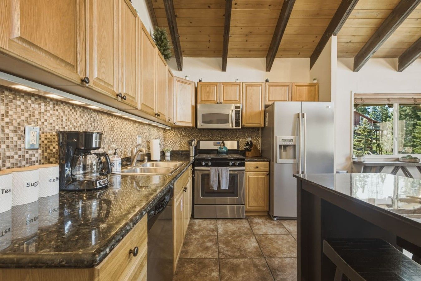 A kitchen with wooden cabinets, stainless steel appliances, a coffee maker, and a tiled backsplash.