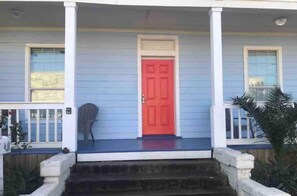 A house with a red door, a porch, and a small chair.