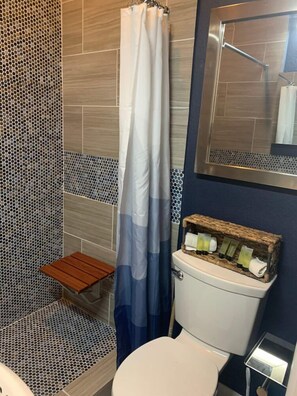 Un baño con ducha, inodoro y un pequeño taburete de madera.