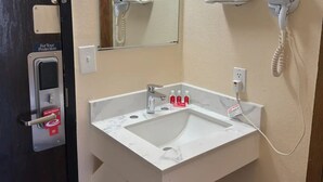 Un baño con un lavamanos blanco, un secador de manos, un espejo y un teléfono.
