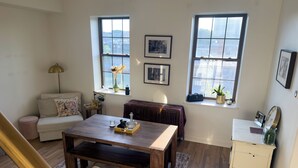 A living room with a sofa, coffee table, and two windows with city views. - Luxury Urban Retreat with Private Rooftop Views of Manhattan (Hoboken)