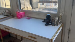A room with a white desk, a window with a city view, a white ottoman, and a door. - Luxury Urban Retreat with Private Rooftop Views of Manhattan (Hoboken)
