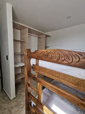 Ein Etagenbett mit Holz Kopfteil, ein begehbarer Kleiderschrank mit offenen Regalen und ein Marmorboden.