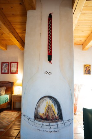 Ein Zimmer mit Kamin, Holzbalken an der Decke, einem Bett und Kunstwerken an den Wänden.