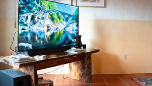 Televisio on sijoitettu puiseen jalustaan, ja sen alla on laatoitettu lattia. Katossa on näkyvillä olevat palkit.