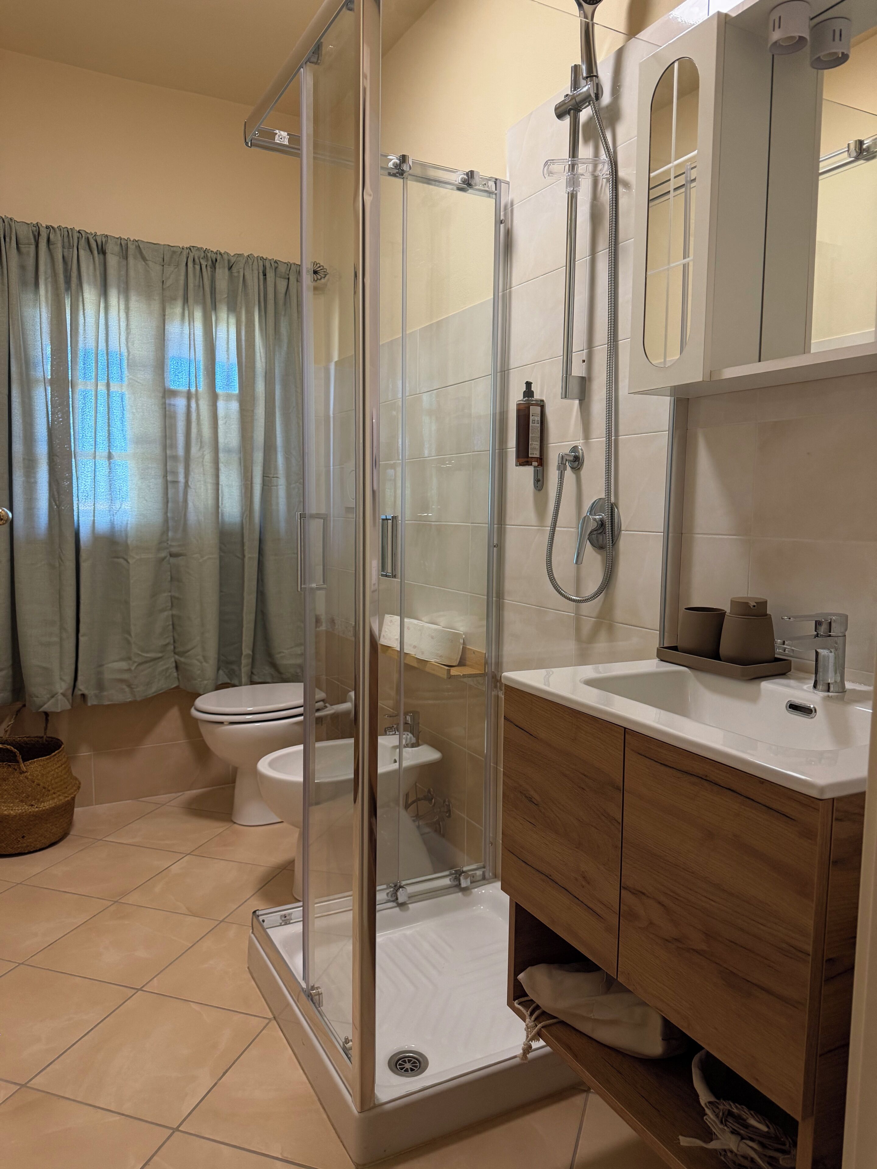 Une salle de bain avec une douche à parois de verre, des toilettes, un lavabo et un miroir.
