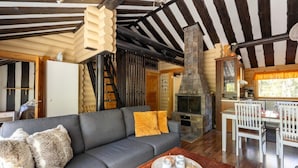 A cozy cabin interior with a sofa, a fireplace, and a dining area.