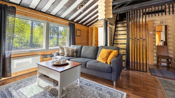 A cozy cabin interior with a sofa, table, and large windows.