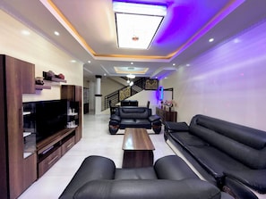 Una sala de estar moderna con un sofá, una mesa de centro, un televisor y una escalera que sube a otro nivel.