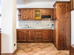 A kitchen with wooden cabinets, a tiled backsplash, and a tiled floor. - Chalet Remondet by Interhome (Sarre)