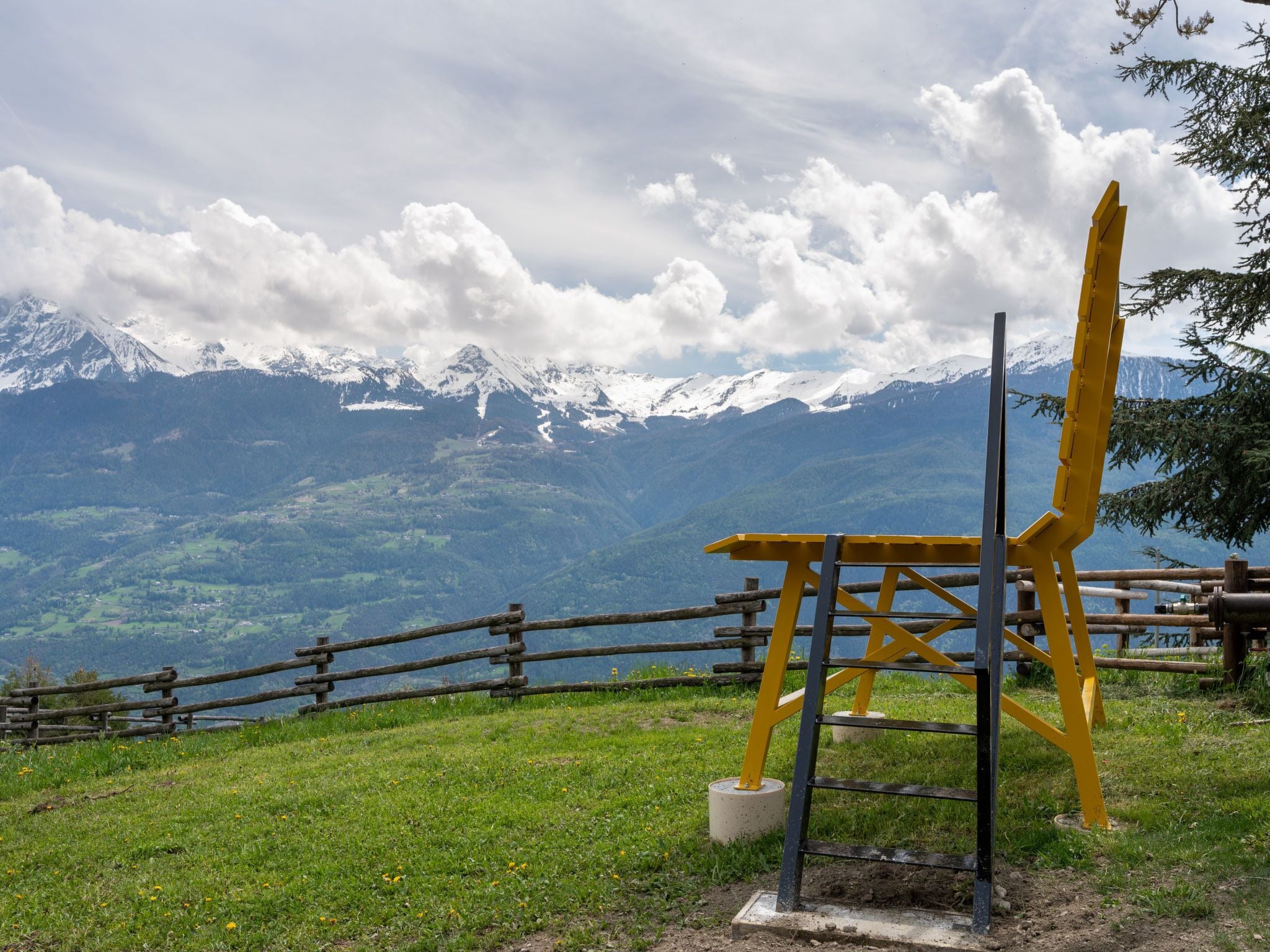 Vista de la montaña con una valla de madera y una silla amarilla.