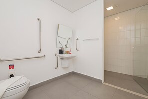 Ein Badezimmer mit Toilette, Waschbecken, Spiegel und Haltegriffen.