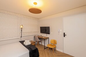 Ein Hotelzimmer mit Bett, Schreibtisch, Stuhl, Fernseher und einer Tür.
