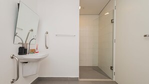 A modern bathroom with a sink, mirror, and handrails. - VNM - VN Vila Olimpia by Anora Spaces (São Paulo)