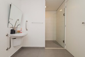Ein modernes Badezimmer mit Waschbecken, Spiegel und Haltegriffen.