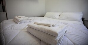 A neatly made bed with folded towels and pillows. - Piazzale Unità d'Italia 3B (Udine)