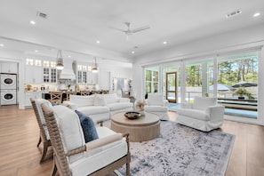 A spacious living room with a large window, a dining area, and a kitchen.
