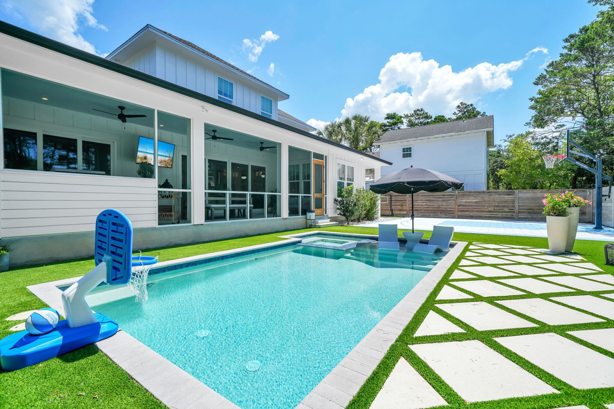 Ein modernes Haus mit Swimmingpool, überdachter Terrasse und Basketballkorb.