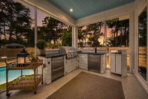Eine Küche mit Grill, Pool und Blick auf Bäume.