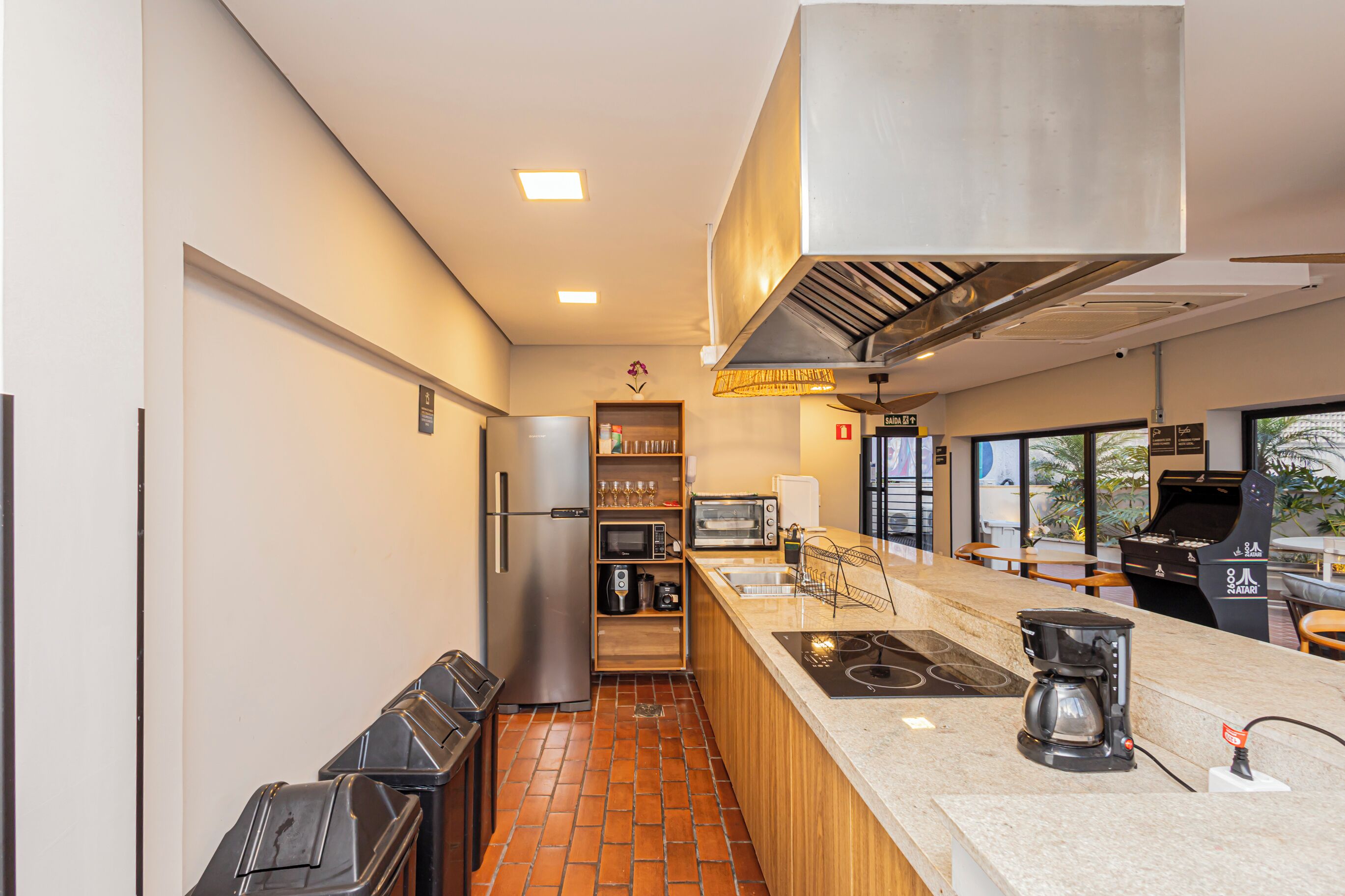 A modern kitchen with a stainless steel refrigerator, a built-in oven, and a coffee machine.