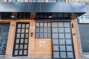 A building with a black metal awning, a brick facade, and a large glass door with a grid pattern. - One House by Anora Spaces (São Paulo)