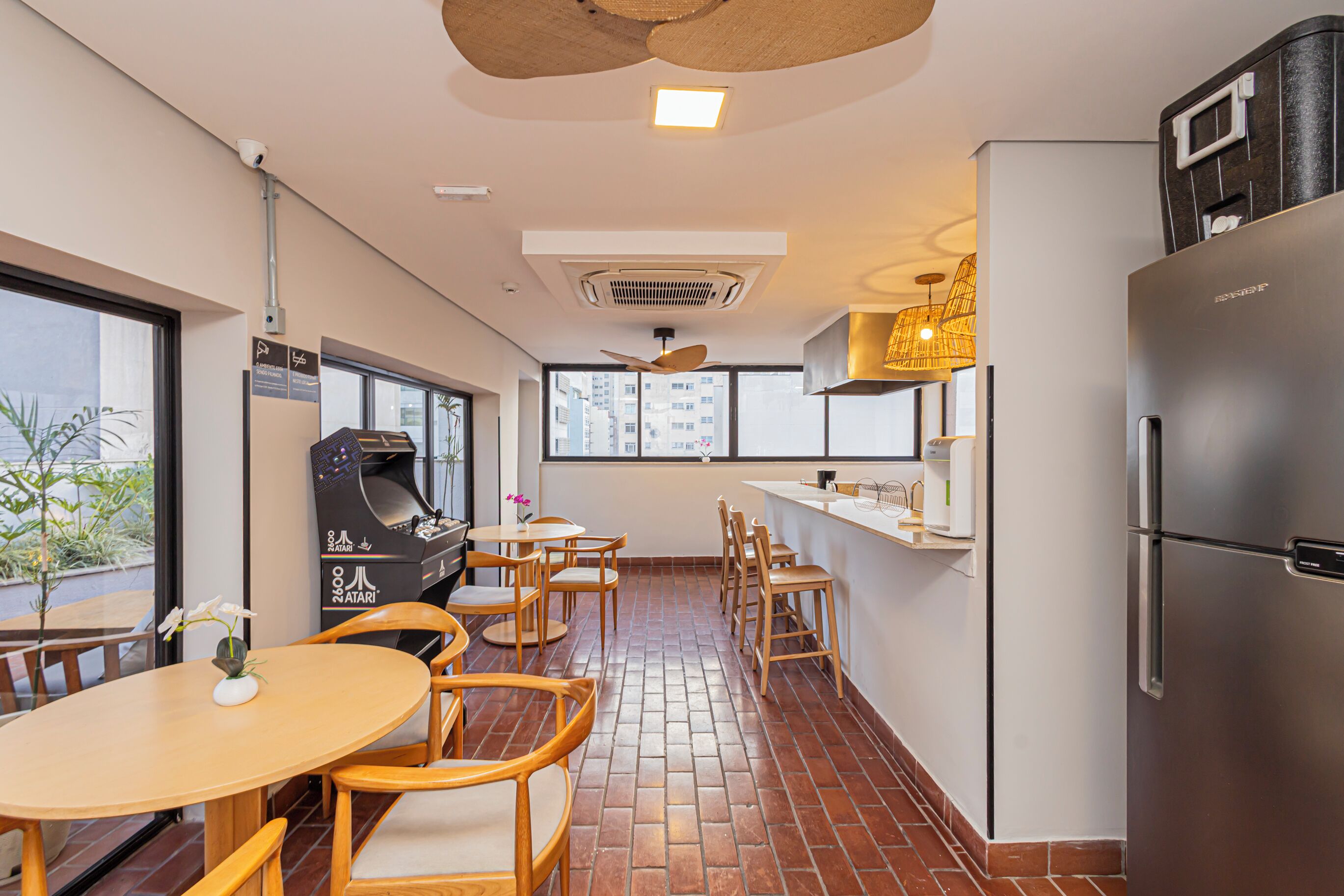A compact kitchen with a refrigerator, a dining area with chairs and a table, and a ceiling fan.