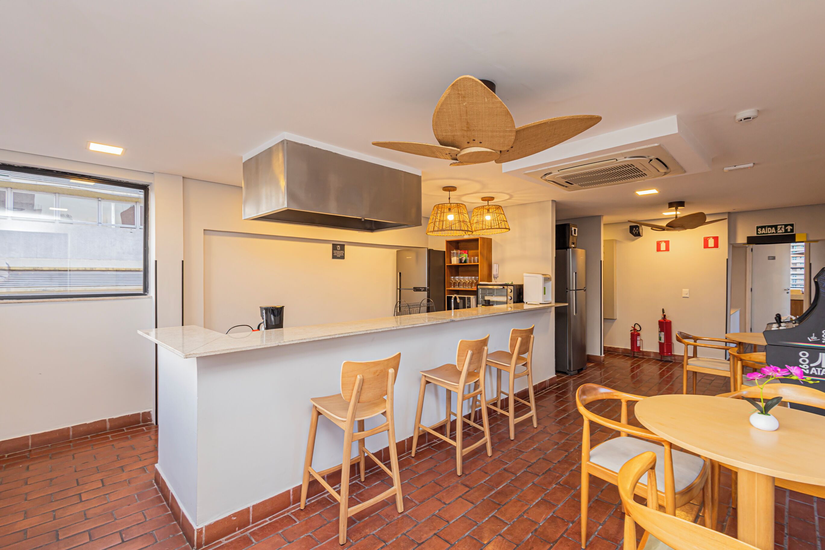 Une cuisine moderne avec un coin bar, des chaises en bois et un ventilateur de plafond.