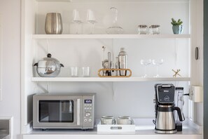 A kitchen with a microwave, coffee maker, and shelves with glassware and kitchen utensils. - Waterfront Studio, newly renovated, A Cool Studio, Glen Arbor M22 Crystal River (Glen Arbor)