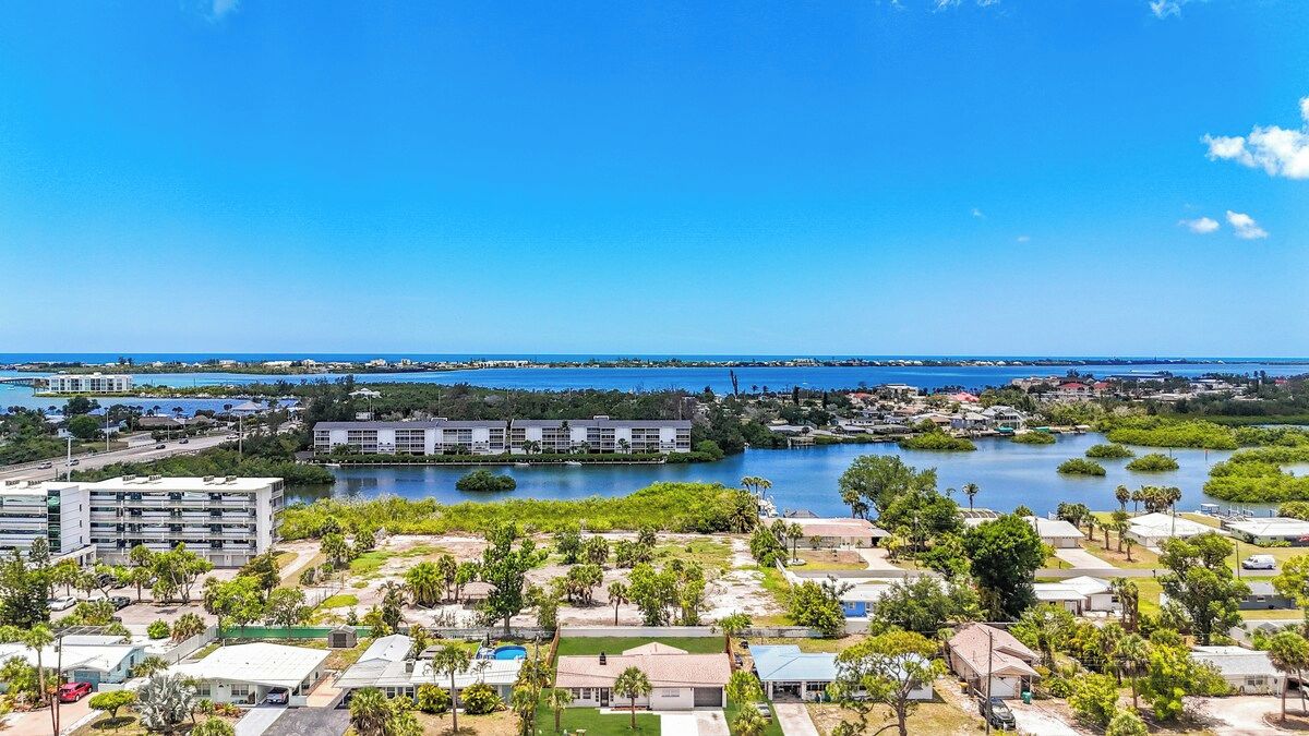 A coastal area with a marina, buildings, and greenery.