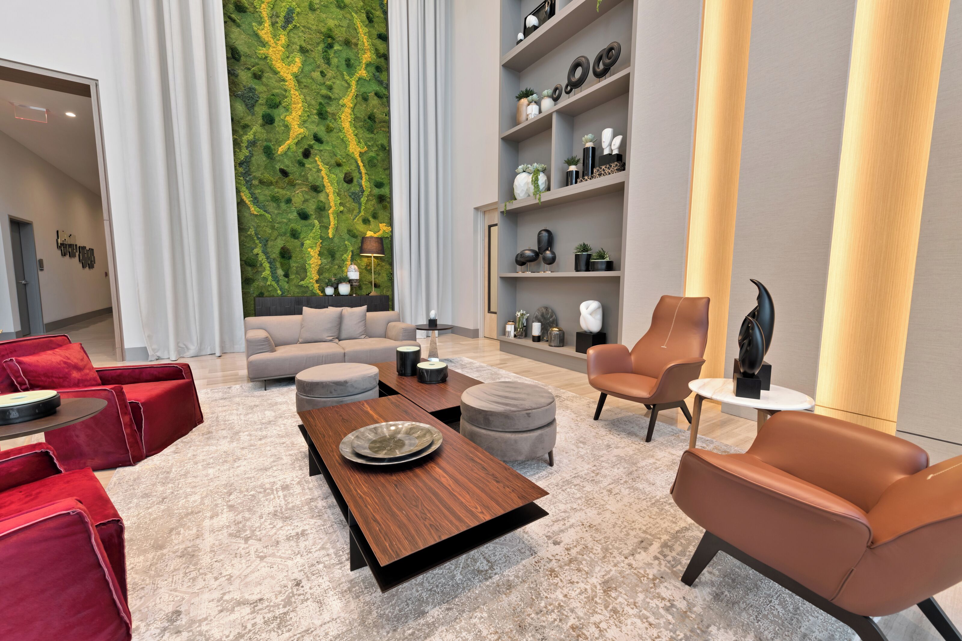 A modern living room with a sofa, red chairs, a coffee table, and a bookshelf.