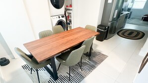 Une cuisine moderne équipée d’un lave-linge intégré, un coin repas avec une table et des chaises en bois, et une vue sur l’espace de vie adjacent.