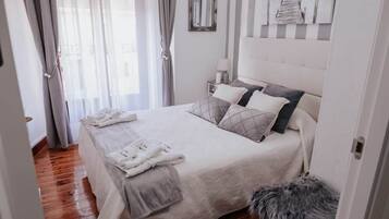Une chambre à coucher bien rangée, avec un lit, des oreillers, une table de chevet, un miroir et un tapis moelleux.