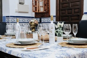 A dining table set with plates, glasses, and a bottle of wine, with a blue and white tiled backsplash in the background. - El Puente Grande Country House · Pool and Garden (Navahermosa)