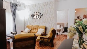 Ein Wohnzimmer mit einer Couch, Sesseln, einem Chandelier, einer Spiegelwand und einem Gemälde.