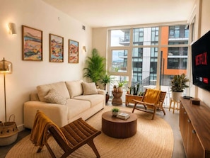 A modern living room with a sofa, two armchairs, a coffee table, and a TV. - Paloma | Resort-Style Lakeshore Condo with Pool (Kelowna)