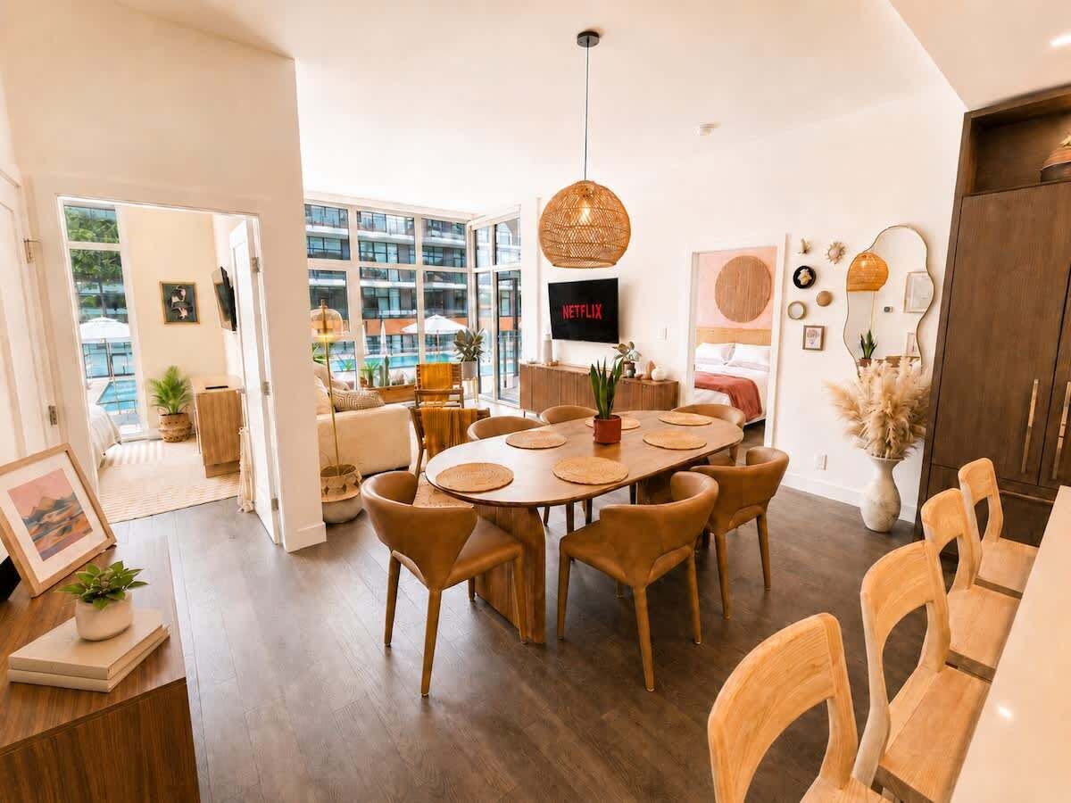 A modern dining area with a round table, chairs, and a hanging light fixture.