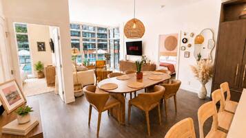 A modern dining area with a round table, chairs, and a hanging light fixture.