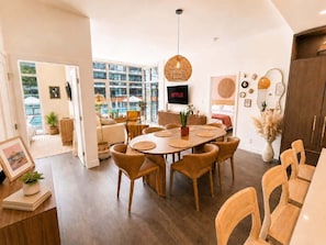 A modern dining area with a round table, chairs, and a hanging light fixture. - Paloma | Resort-Style Lakeshore Condo with Pool (Kelowna)