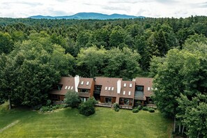A modern two-story house with a sloped roof, surrounded by dense forest. - New Listing! Peaceful 3-bedroom condo in Stowe - access to the Rec Path and more (Stowe)