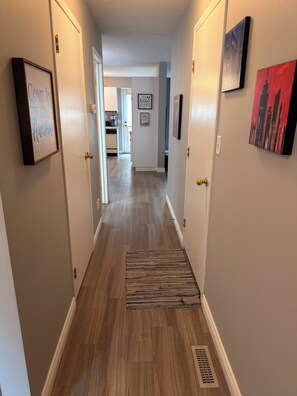Un couloir doté d’un plancher en bois, d’un tapis et d’œuvres d’art encadrées accrochées aux murs.