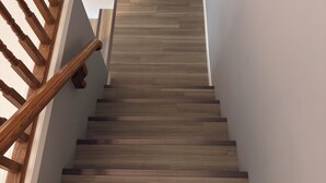 Una escalera de madera con pared blanca y peldaños alfombrados.