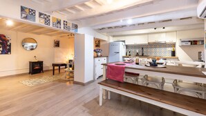 A modern kitchen with white cabinets, a wooden dining table, and a patterned backsplash.