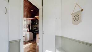A hallway leading to a kitchen with wooden flooring, white walls, and a hanging sign that reads 'HOME sweet HOME'. - 4 Bedroom Main Cottage XIV: PL (Gravenhurst)
