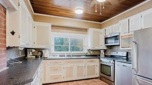 A kitchen with white cabinets, a window, a stove, a microwave, and a refrigerator. - 4 Bedroom Main Cottage XIV: PL (Gravenhurst)