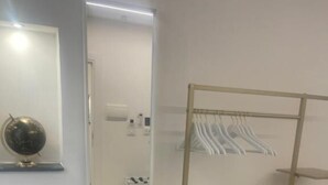 Una silla color turquesa, un perchero con marco dorado y un espejo en la pared.
