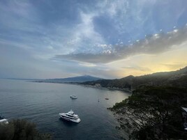 Eine Küstenansicht mit einer Yacht, ruhiger See und entfernten Bergen.