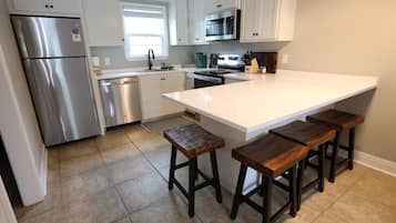 Una cocina moderna con electrodomésticos de acero inoxidable, una isla grande con taburetes de bar y armarios blancos.
